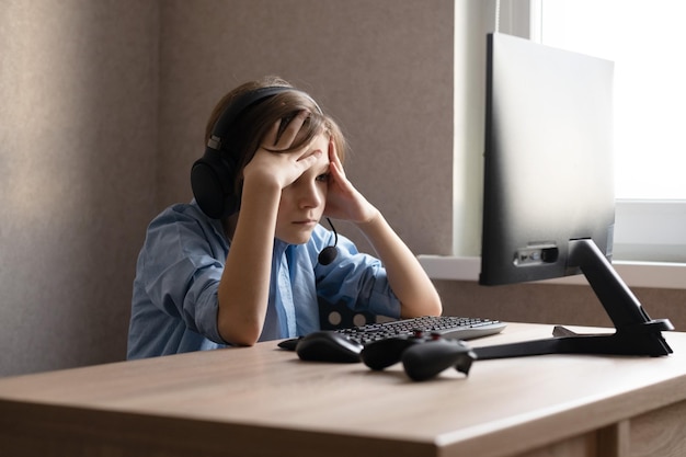 Um adolescente está sentado em casa no computador e jogando jogos de computador online.