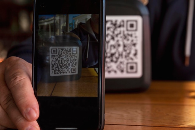 Um homem mostra o código QR ao telefone em um café. Vacinação obrigatória e digitalização da população. Fechar-se.