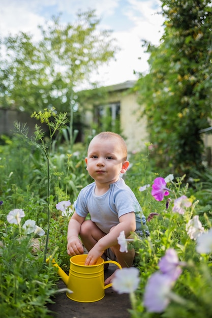 Um menino ajudante está sentado no jardim com um regador amarelo