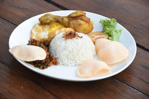 Foto um prato de comida com arroz e ovo frito, biscoitos de frango fritos e sambal