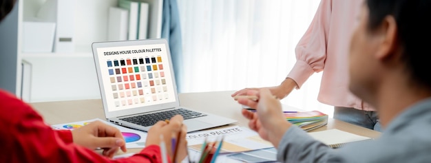 Um retrato da criatividade da equipe de designer gráfico seleciona a cor apropriada para o projeto usando o laptop na mesa com equipamentos e ferramentas de design espalhadas no escritório moderno Closeup Variegado