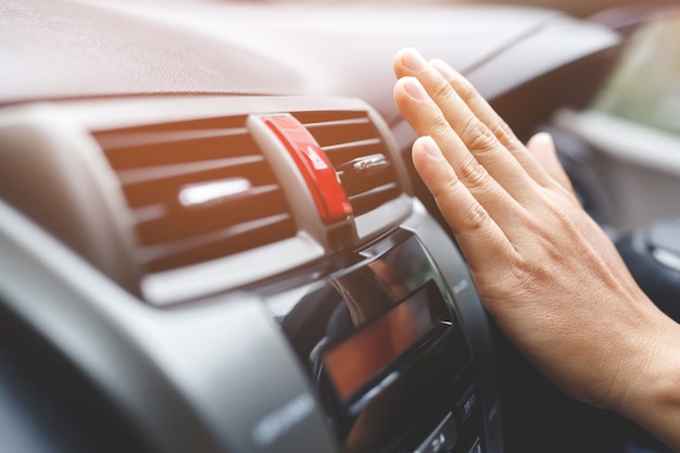 Uma mão masculina verificando o resfriamento do ar condicionado no carro