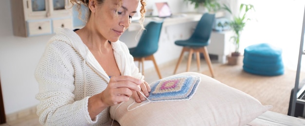 Uma mulher em casa fazendo trabalho de bordado em uma almofada de decoração branca para hobby e atividade de lazer interna sozinha sentada à mesa Vida real em apartamento para mulheres solteiras aproveitando o tempo