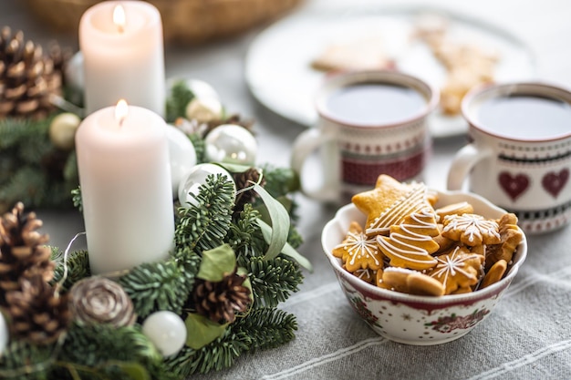 Uma tigela cheia de pão de Natal na mesa levou uma coroa do Advento e duas xícaras com ponche de café ou chá