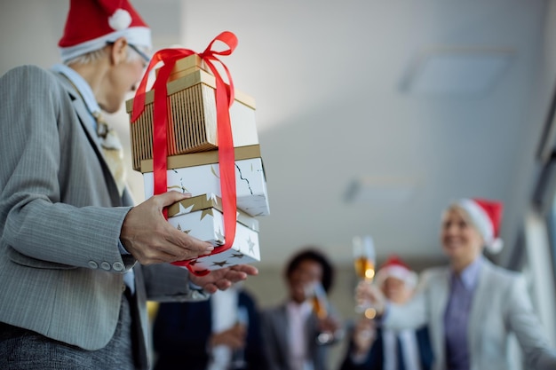 Untere Ansicht einer Geschäftsfrau, die ihre Kollegen auf einer Büroparty mit Weihnachtsgeschenken überrascht