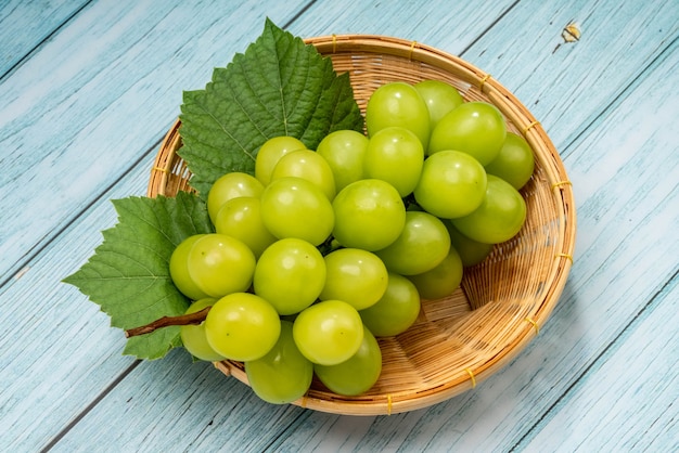 Uva verde doce na cesta Uva Shine Muscat na cesta no fundo azul de madeira