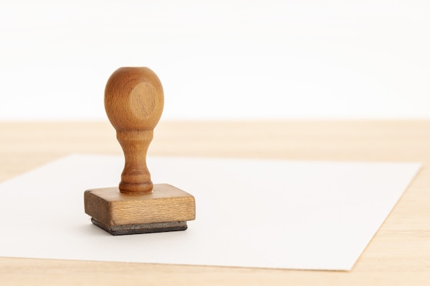 Foto vintage-stempel und leeres papier auf holztisch. weißer hintergrund. platz kopieren