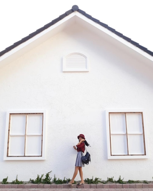 Foto vista lateral de mulher com mochila de pé contra a casa