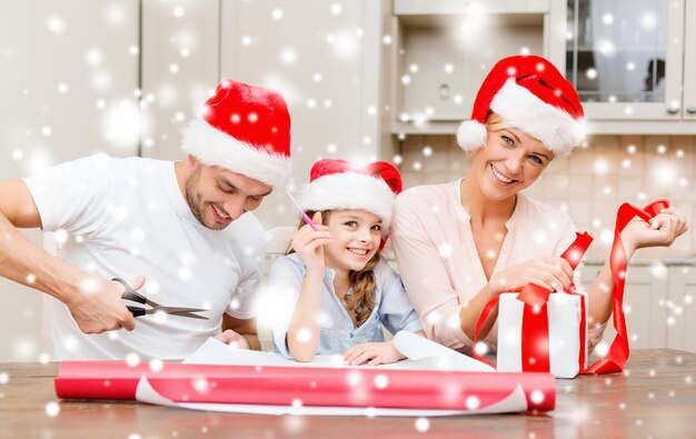 Weihnachts-, Weihnachts-, Winter-, Familien-, Glücks- und Menschenkonzept - lächelnde Familie in Weihnachtsmann-Helferhüten mit Geschenkbox