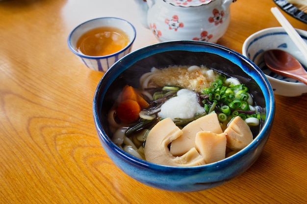 Winter Udon mit heißem Tee auf hölzerner Tabelle.