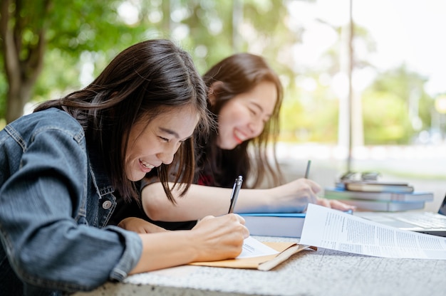 Foto zwei asiatische studenten arbeiten zusammen an einer abschlussarbeit, um lehrer an universitäten zu entsenden