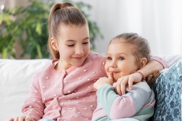 Foto zwei glückliche lächelnde kleine mädchen oder schwestern zu hause