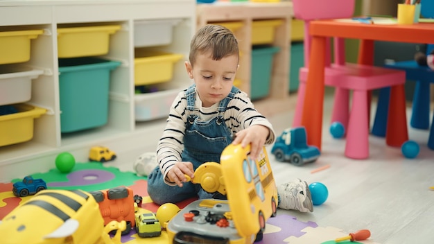 Free Photo adorable caucasian boy playing with toys sitting on floor at kindergarten