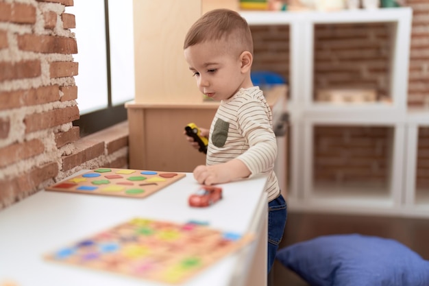 Free Photo adorable toddler playing with cars toys on table at home