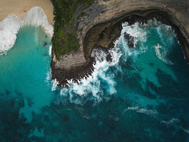 Aerial shot of the cliffs covered in greenery surrounded by the sea