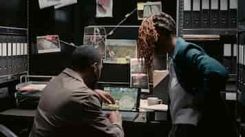 Free photo african american officers examining criminal records in incident room, planning private investigation in police archive. man and woman investors analyzing case files, reading statements.