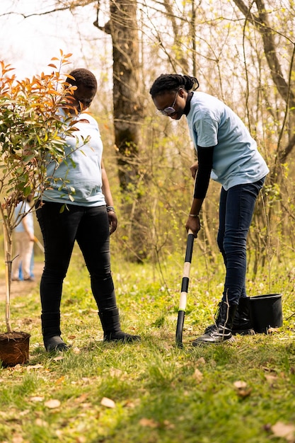 Free photo african american women digging holes with a shovel and planting tree