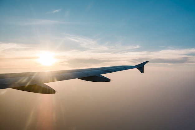 Foto gratuita ala e tramonto dell'aeroplano su cielo blu