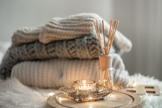 Aroma bamboo sticks in a bottle with scented liquid with candles staying on a wooden tray on blurred background.