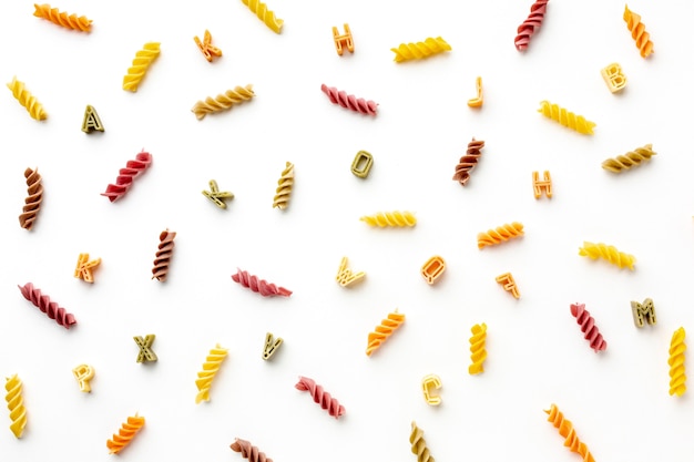 Free photo arrangement of uncooked colorful fusilli and alphabet pasta