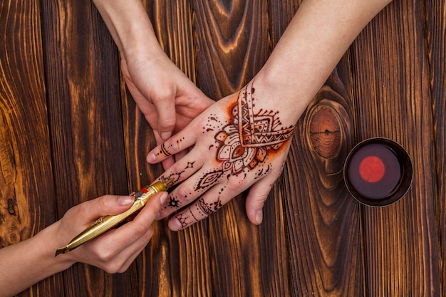 Free Photo artist making mehndi on womans hand near tea cup