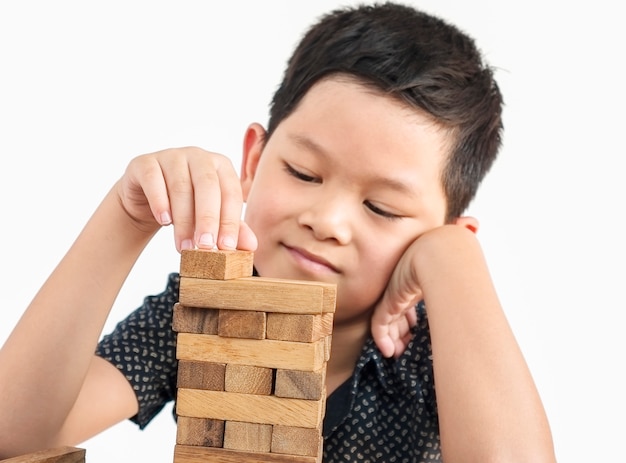 Free Photo asian kid is playing jenga, a wood blocks tower game 