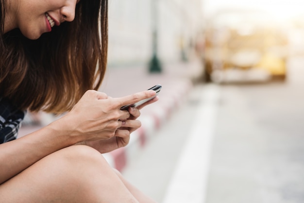 Free photo asian woman tourist backpacker smiling and using smartphone traveling alone