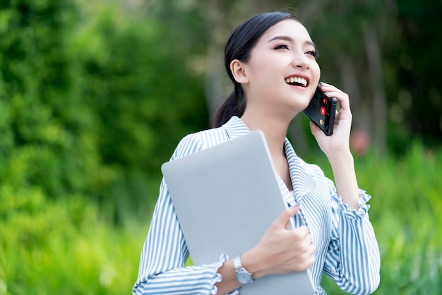 Free photo attractive smile cheerful asian female businesswoman laptop connectin communication technology building garden outdoor location free copysapce