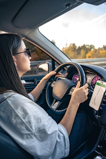 無料Photo 車を運転する魅力的な若い女性がナビゲーターを使用しています