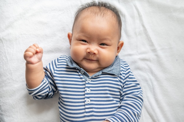 Free Photo baby lying face up on a white bed