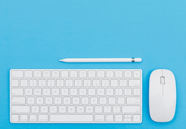 Back to school concept with pencil, keyboard, mouse on blue background flat lay.