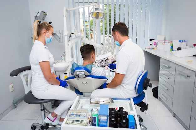 Foto gratuita punto di vista posteriore del paziente e del dentista in ufficio