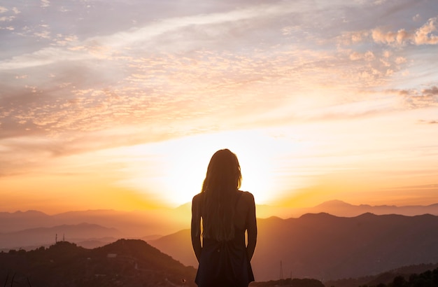 Free Photo back view of woman doing yoga while watching the sunset