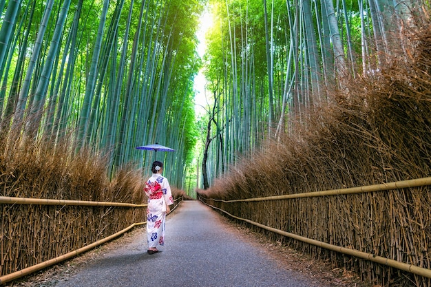 Free photo bamboo forest. asian woman wearing japanese traditional kimono at bamboo forest in kyoto, japan.