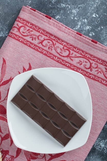 Bar of delicious chocolate on a white plate .