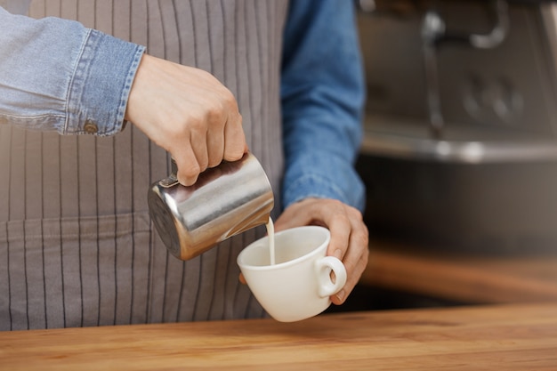 Free photo barista making cup of latte, pouring milk into cup.