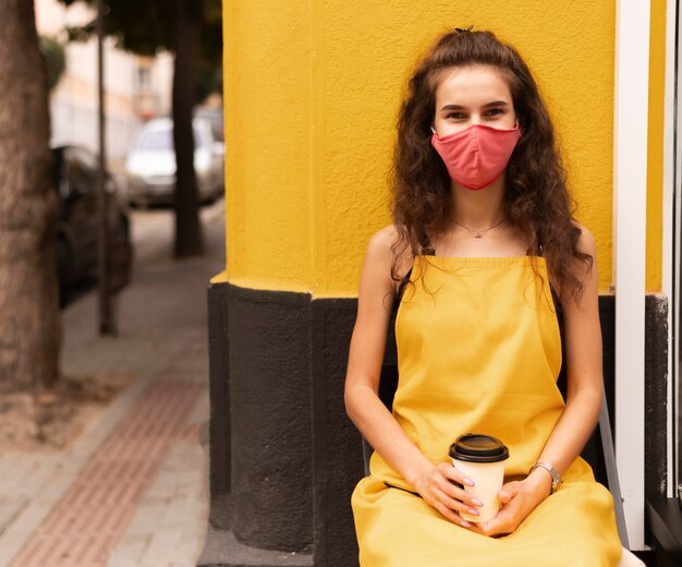 Free photo barista wearing a face mask while holding a cup of coffee outside