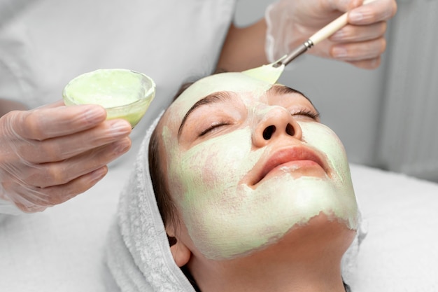 Free photo beautician applying face mask on female client