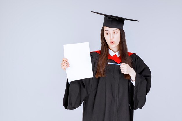 Beautiful female student paper and pen in hands posing. High quality photo