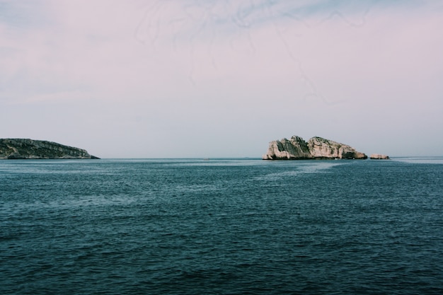 Free photo beautiful shot of the sea with rocks and cliffs under a cloudy sky