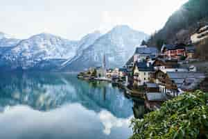 Foto gratuita bellissimo scatto di un piccolo villaggio circondato da un lago e colline innevate