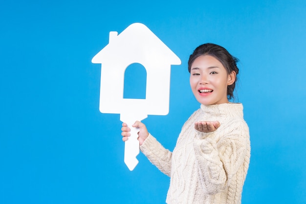 Free photo a beautiful woman wearing a new long sleeved white shirt with a house symbol  . house trading .