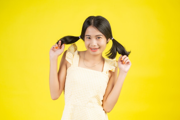 Free photo a beautiful woman who is happy showing various gestures on a yellow .