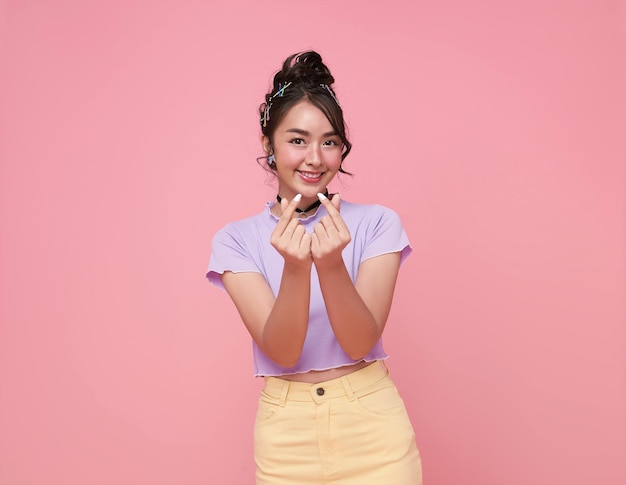 Free Photo beautiful young asian cute woman shows mini heart fingers isolated on pink background