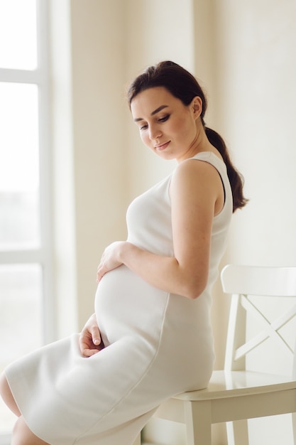 Free photo beautiful young pregnant woman posing in studio in dress