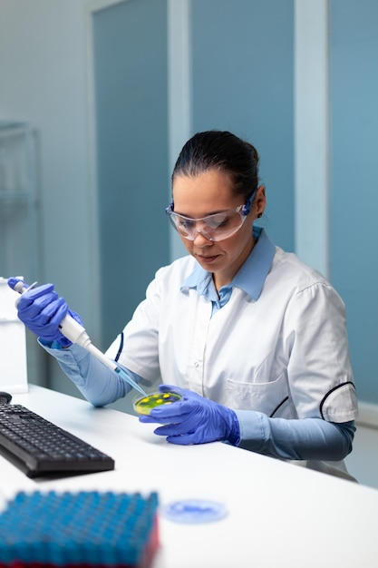 Free Photo biochemist researcher woman dropping liquid in petri dish with colony fungi