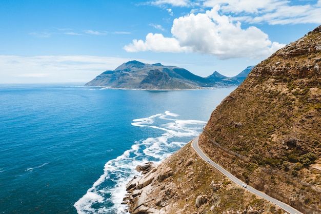 Free photo bird's-eye shot of a beautiful road on a mountain near a body of water during the day