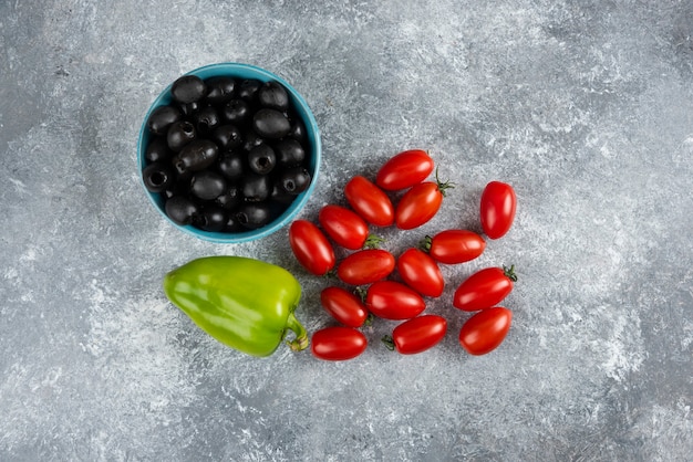 Free photo black olives, pepper and tomatoes on marble.