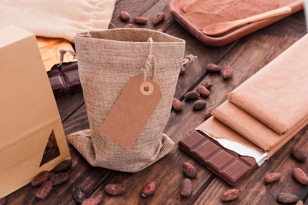 Free photo blank tag on sack with scattered cocoa beans and chocolate bar on table