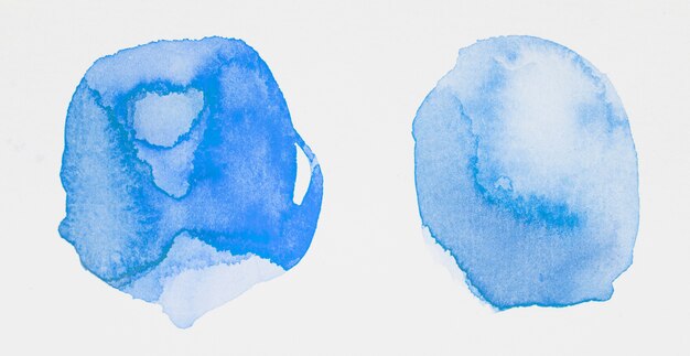 Blue paints in form of circles on white paper